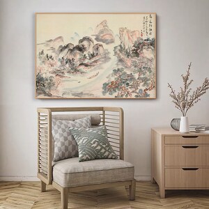 May include: A traditional Chinese landscape painting depicting mountains, trees, and a river. The painting is executed in shades of grey, blue, and pink, with a few touches of red. The painting is framed in a simple wooden frame.