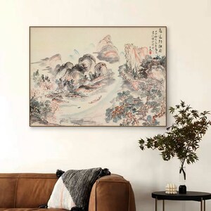 May include: A traditional Chinese ink and wash painting depicting a landscape with mountains, trees, and a river. The painting is done in shades of blue, grey, and pink, with hints of red and orange. The painting is framed in a simple wooden frame.