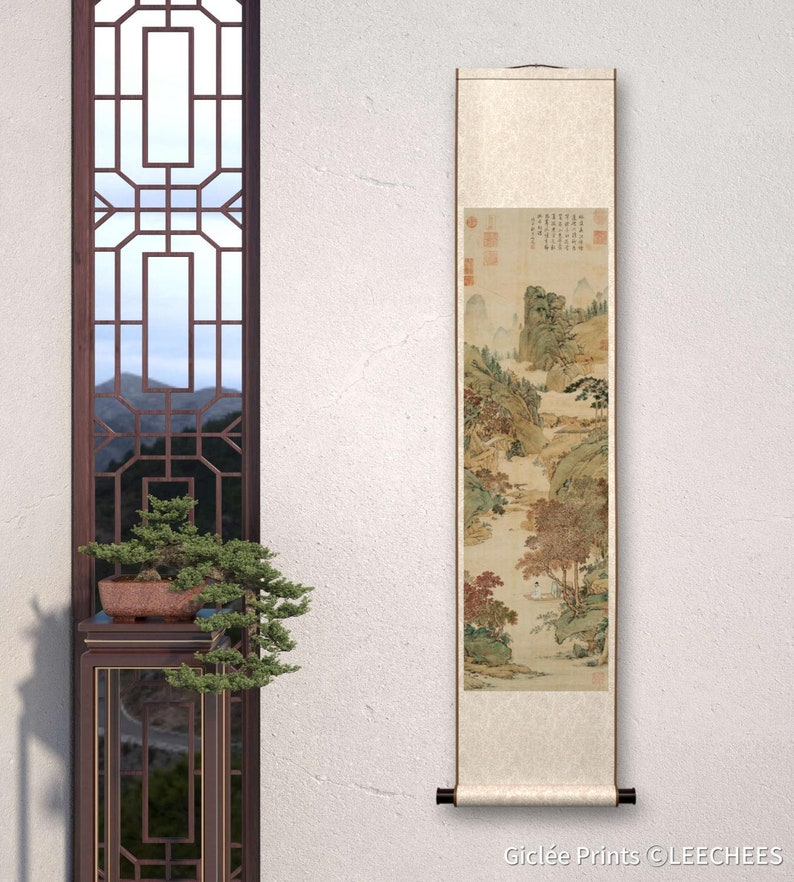 May include: A traditional Chinese scroll painting depicting a landscape scene with mountains, trees, and a river. The painting is done in shades of brown, green, and white, and features a small figure in a boat on the river. The scroll is mounted on a wooden dowel and has a decorative tassel.