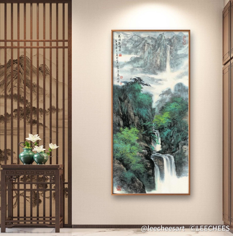 May include: A traditional Chinese ink and wash painting depicting a waterfall cascading down a mountainside. The painting is framed in a wooden frame and features a light gray background with green and blue hues. The painting is signed in Chinese characters.