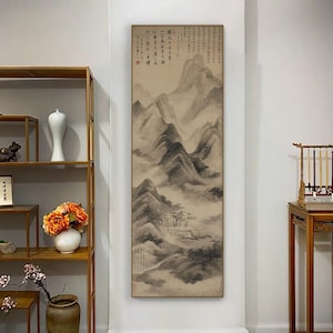 以下が含まれることがあります： 薄い茶色の背景に、山岳風景を描いた白黒の墨絵。絵は額装され、白い壁にかけられている。絵には右上に中国語の文字が書かれている。