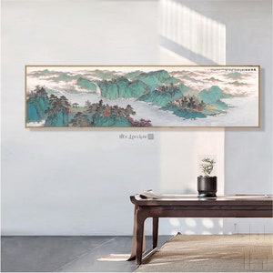 Pode incluir: Uma pintura longa e horizontal que retrata uma paisagem montanhosa nebulosa com um rio serpenteando por ela. A pintura é emoldurada por uma moldura fina e dourada e está pendurada em uma parede branca.