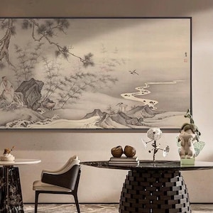 Könnte beinhalten: Innenraum mit einem großen, gerahmten Landschaftsgemälde in Grau- und Weißtönen. Ein runder Tisch mit dunkler, strukturierter Basis befindet sich im Vordergrund, zusammen mit einem Stuhl und dekorativen Objekten.