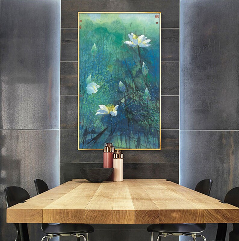 May include: A framed watercolor painting of white lotus flowers in a green and blue landscape. The painting is hanging on a wall above a wooden table with two chairs.