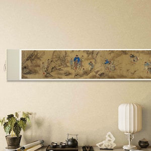 May include: A vintage-style scroll painting depicting a group of people in a mountainous landscape. The painting is framed and hanging on a wall above a table with a lamp, a teapot, and other decorative items.