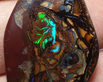 May include: A brown, green, and blue opal gemstone with a unique, swirling pattern. The opal is cut into a teardrop shape and has a high polish.