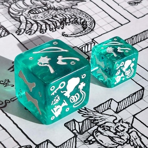 Può includere: Due dadi traslucidi color turchese con icone bianche e argentate, tra cui un osso, una chiave e un'arma, sono su una mappa di dungeon disegnata a mano. I dadi sono di dimensioni diverse, quello più grande in primo piano.