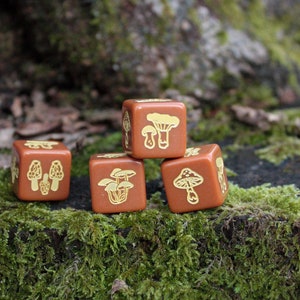 May include: Four brown dice with gold mushroom illustrations. The dice are stacked in a pyramid shape on a bed of green moss.