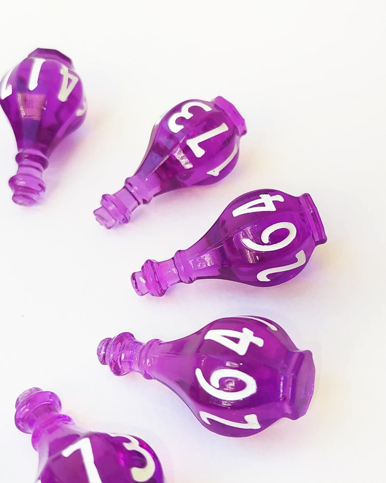 May include: Five translucent purple bottle-shaped beads, each featuring white printed numbers. The beads have a narrow neck and a rounded body, with visible numbers including 41, 173, 264, and 13. The objects are arranged in a scattered pattern.