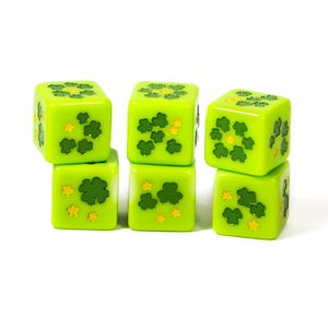 May include: A set of five lime green six-sided dice featuring dark green shamrock patterns and small yellow flower accents on each face. The dice are arranged in three stacks, with two stacks of two dice and one single die positioned on the right side.