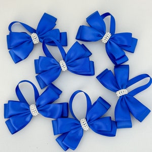 May include: Six royal blue satin bows with a single row of clear rhinestones in the centre of each bow.