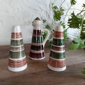 May include: Three ceramic salt and pepper shakers with a green, brown and white striped design. The shakers are cone-shaped and have a decorative pattern.