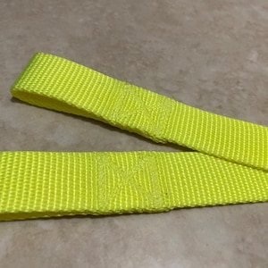May include: A pair of bright yellow nylon straps, likely used for towing or securing objects.