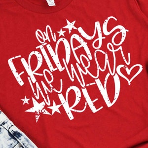 May include: Red t-shirt with white text that says "On Fridays we wear red" with a heart and stars.
