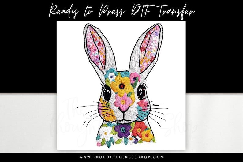 May include: A white rabbit with colourful floral embroidery on its ears, face, and neck. The embroidery features a variety of flowers in pink, yellow, blue, and green.