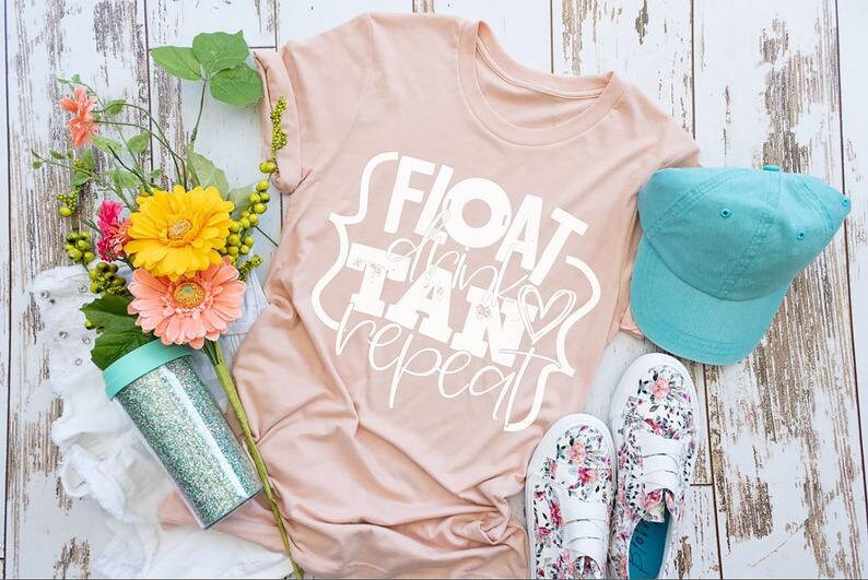 May include: A light pink t-shirt with the words "FLOAT, TAN, repeat" in white script, a turquoise baseball cap, and floral print shoes. A glittery tumbler and flowers are also in the image.
