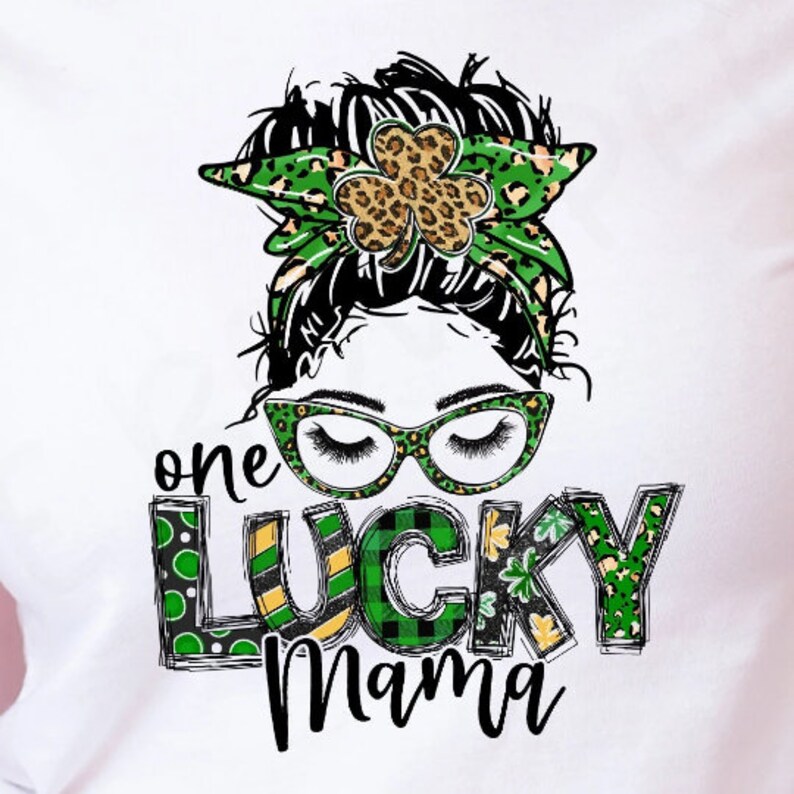 May include: A white t-shirt with a green, black, and gold graphic design. The graphic features a woman with a messy bun, glasses, and a shamrock headband. The text "one lucky mama" is written in a green, black, and gold font.