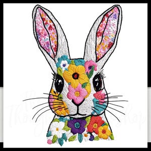 May include: A white rabbit with floral embroidery on its face and ears. The flowers are in shades of pink, yellow, blue, and green.