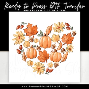 May include: A heart-shaped design featuring autumn-themed elements, including pumpkins, leaves, and flowers. The design is perfect for creating iron-on transfers for clothing or other fabric projects.