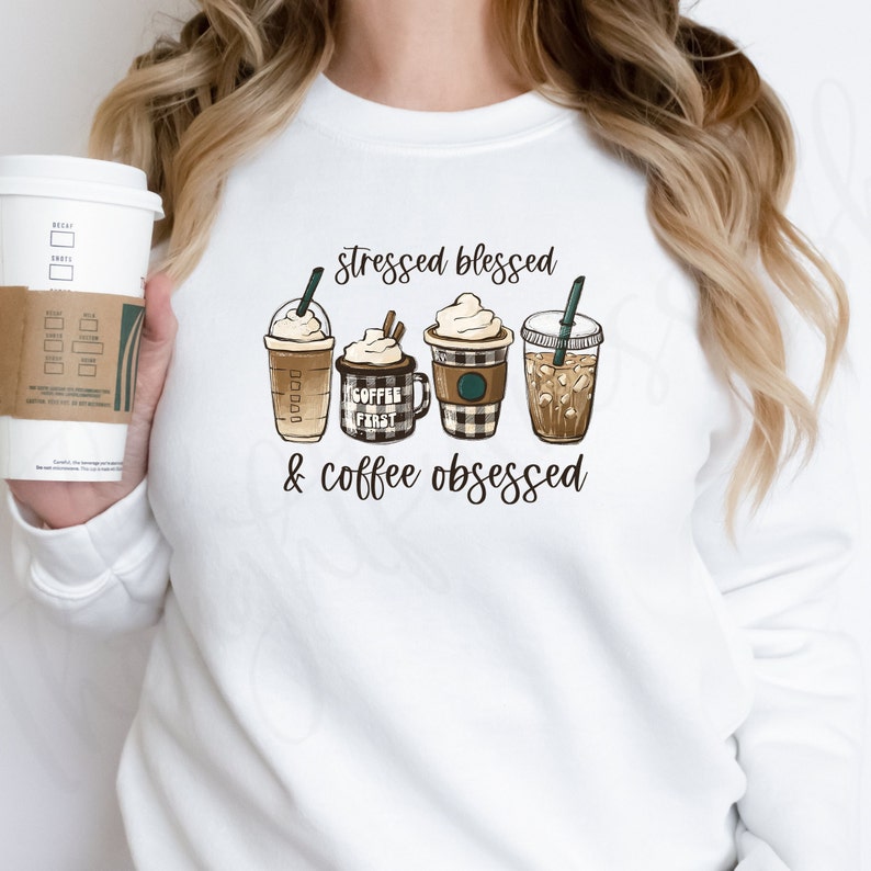 May include: White sweatshirt with the text "stressed blessed & coffee obsessed" and a graphic of four coffee drinks. The coffee drinks are a caramel macchiato, a coffee mug with the text "coffee first", a peppermint mocha, and an iced coffee.