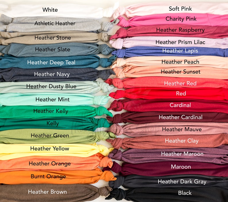 May include: A collection of folded t-shirts in various colors, including white, gray, pink, red, and black. Each shirt is labeled with its color name, such as "Heather Slate," "Heather Kelly," and "Maroon."