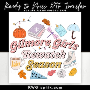 May include: A colorful DTF transfer design featuring the text "Gilmore Girls Rewatch Season" with various illustrations. Includes a pumpkin, books, a dragonfly, a candle, an umbrella, a mug, a skate, and fall leaves. The design also includes the text "Ready to Press DTF Transfer".