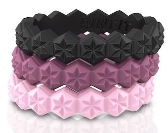 May include: Three silicone rings stacked on top of each other. The top ring is black, the middle ring is a deep purple, and the bottom ring is a light pink. All three rings have a geometric pattern with a star in the center of each hexagon.