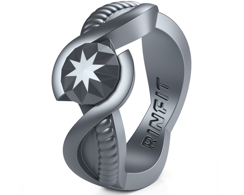 Op de afbeelding: Een zilveren ring met een stervormig ontwerp en het woord "RINFIT" gegraveerd aan de zijkant.