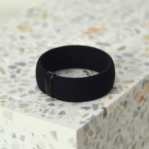 May include: A black silicone ring with a black metal band.