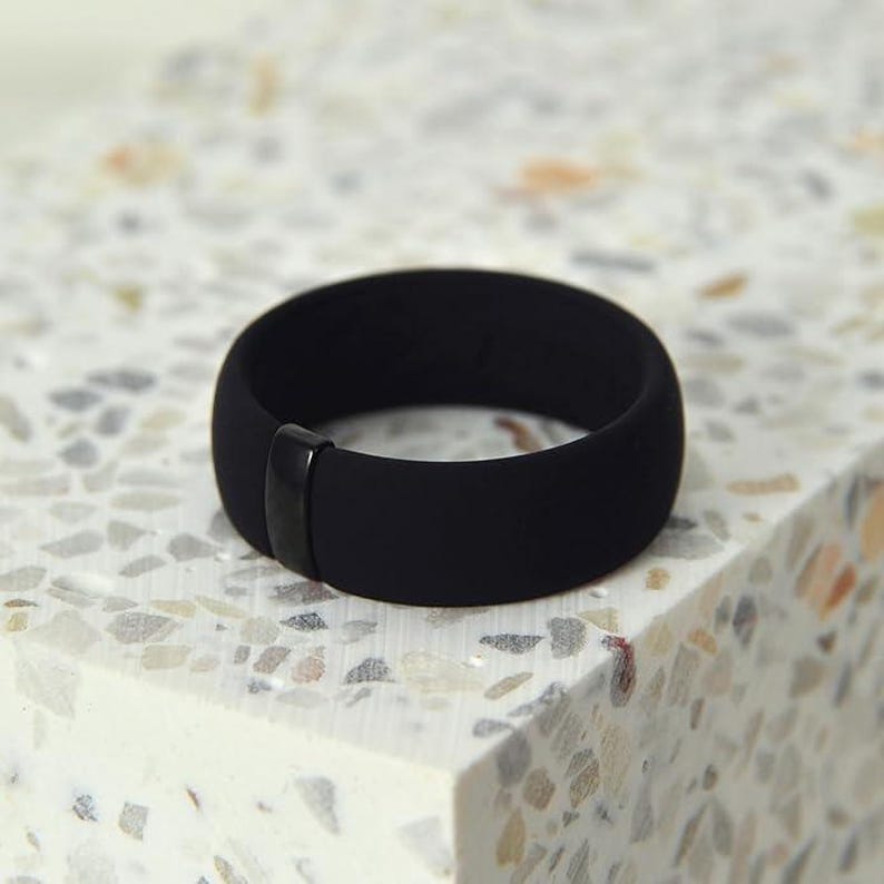 May include: A black silicone ring with a black metal band.
