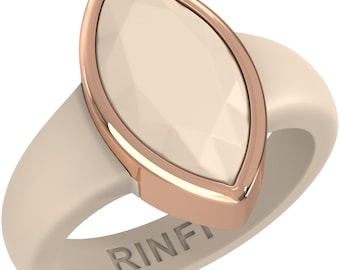 Op de afbeelding: Een crèmekleurige ring met een grote, marquise-vormige, facetgeslepen, gebroken witte steen, gezet in een roségouden bezel. De band heeft een bijpassende crèmekleur. Het woord "RINF" is op de zijkant gegraveerd.