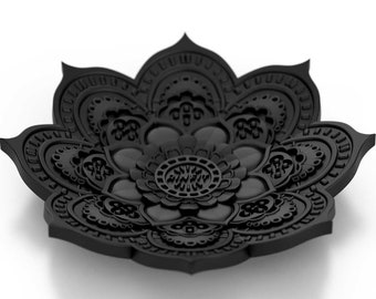 Op de afbeelding: Een zwarte, ingewikkeld ontworpen mandala-vormige schaal met een reliëf, bloemmotief. De schaal is gemaakt van een glad, mat materiaal en heeft een licht afgeronde vorm.