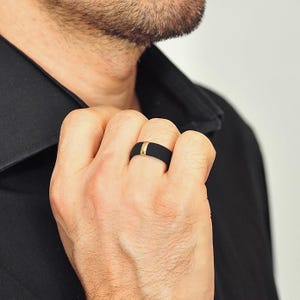May include: A black silicone ring with a thin gold band.
