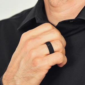 May include: A black silicone ring worn on a person's finger.