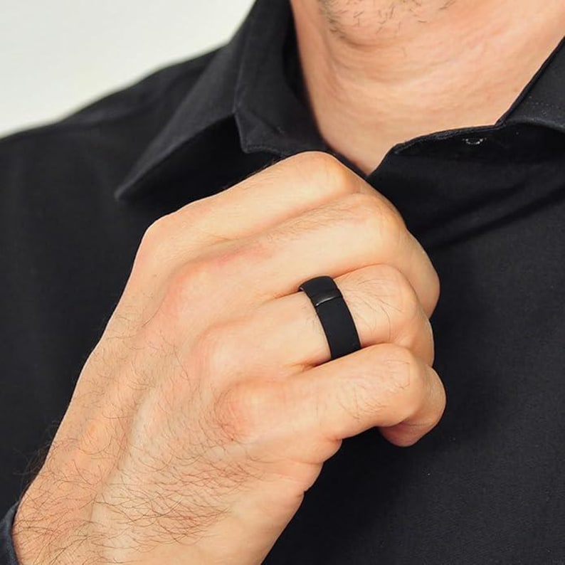 May include: A black silicone ring worn on a person's finger.