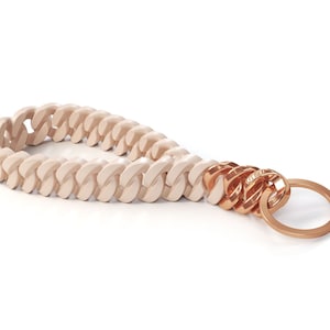 May include: A cream-colored chain keychain with a gold metal ring. The chain is made of a thick, chunky material.