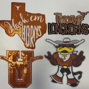 May include: Four embroidered patches featuring Texas Longhorns themes. One is a burnt orange Texas state shape with white 'Hook 'em HORNS' text, one says 'Texas LONGHORNS' with leopard print, one is a 'U' with a longhorn, and one is a mascot character.