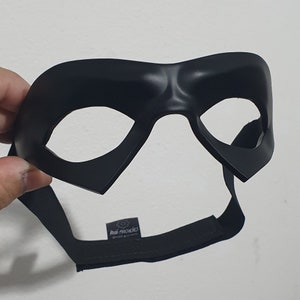 May include: Black plastic mask with a raised design and two eye holes. The mask has a black elastic strap.