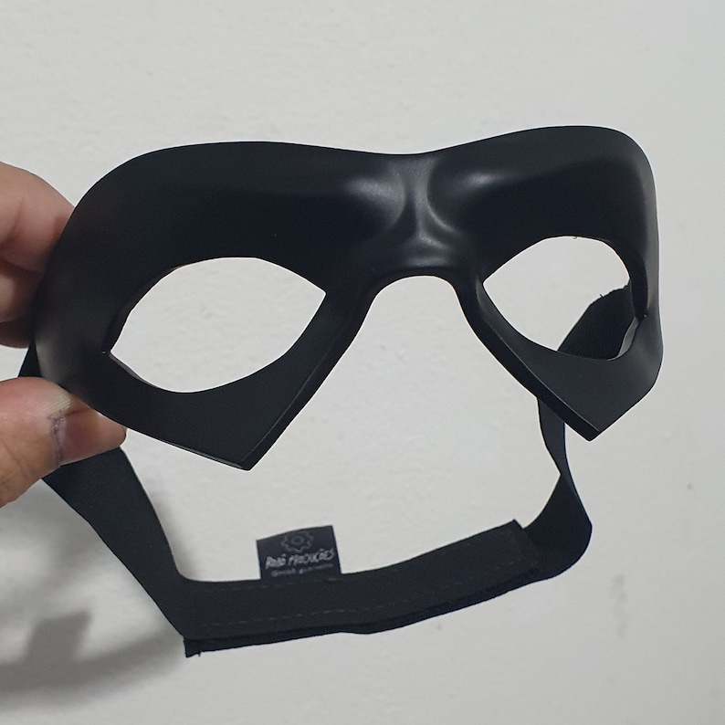 May include: Black plastic mask with a raised design and two eye holes. The mask has a black elastic strap.