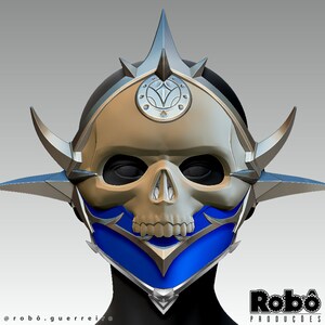 May include: A silver and blue skull mask with a pointed crown and horns. The mask has a blue faceplate with silver accents.