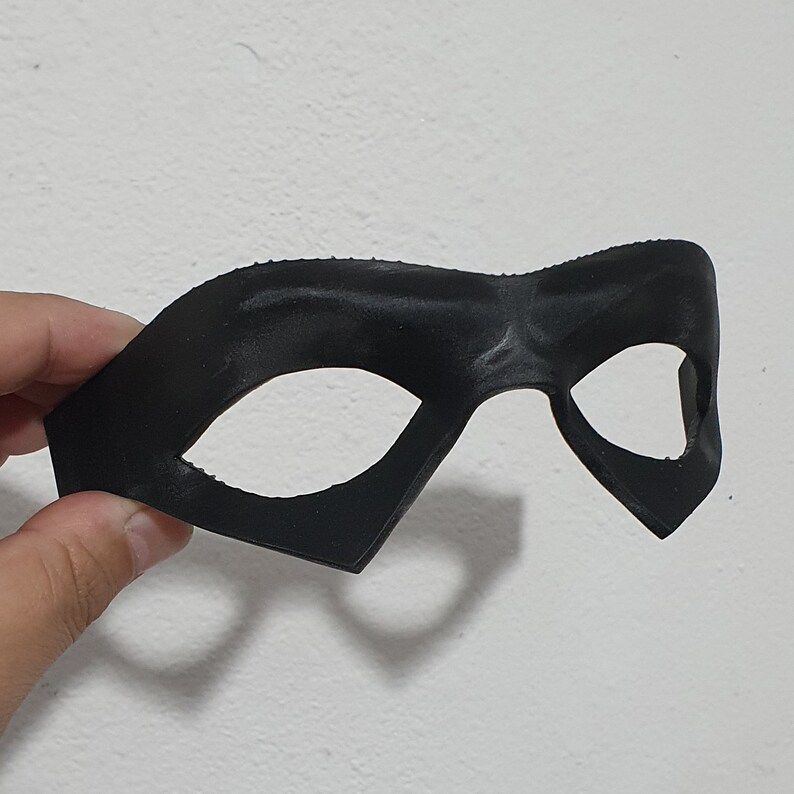 May include: A black plastic eye mask with a simple design. The mask has two eye holes and a curved shape.