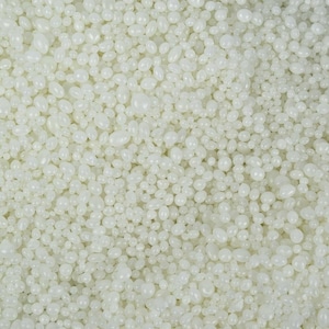 May include: Close-up of a pile of off-white, oval-shaped wax beads. The beads are smooth and have a slightly glossy appearance. The image is well-lit, showing the texture and shape of the beads. These beads are likely used for candle making or other crafts.