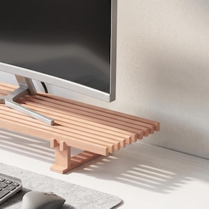 Op de afbeelding: Een monitorstandaard van lichtgekleurd hout met een latjesoppervlak en twee stevige steunpoten. De standaard staat op een bureau en draagt een gebogen computermonitor, met een grijs toetsenbord en een computermuis op een vilten mat eronder.