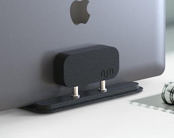 May include: A black laptop stand with a wood grain finish. The stand has two metal posts and the word "num" is engraved on the front. The stand is holding up a silver laptop with an Apple logo.
