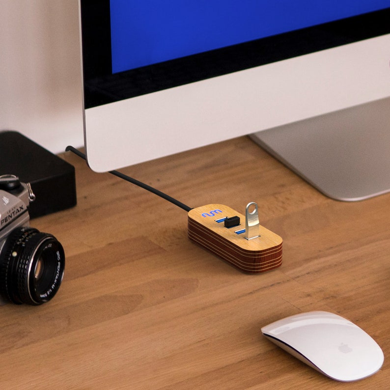 May include: A wooden USB hub with four ports and a blue light indicator. The hub is connected to a computer monitor and a white mouse is on the desk.