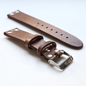 May include: Two brown leather watch straps with silver buckles. The strap on the bottom has a silver stud detail.
