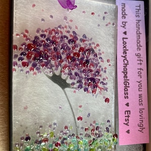 K&ouml;nnte beinhalten: Ein handgemachtes Glaskunstwerk mit einer lila Blume mit gr&uuml;nen und lila Glasakzenten. Das St&uuml;ck ist in einer schwarzen Box mit einer rosa Karte gerahmt, auf der steht: "Dieses handgemachte Geschenk f&uuml;r dich wurde liebevoll hergestellt von &hearts; LoxleyChapelGlass &hearts; Etsy &hearts;".