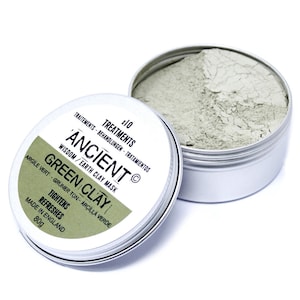 Może przedstawiać: Srebrny pojemnik z zieloną glinką do masek na twarz. Etykieta zawiera napis "Ancient Wisdom/Earth Clay Mask Green Clay Tightens Refreshes Made in England 80g".