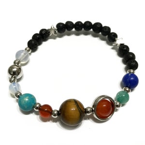 May include: A beaded bracelet with a solar system theme. The bracelet features black lava beads, silver spacer beads, and colourful gemstone beads representing the planets. The bracelet also includes two silver star charms.