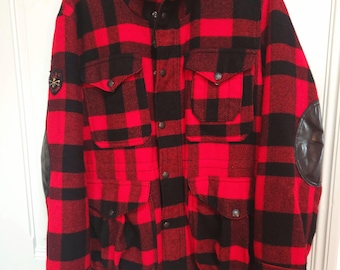 Könnte beinhalten: Eine rote und schwarze karierte Kapuzenjacke mit einem Leder-Patch am Ellbogen. Die Jacke hat mehrere Taschen und einen Kordelzug an der Taille.